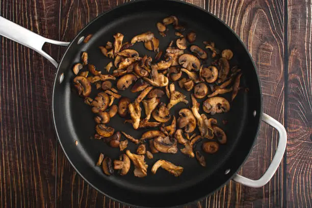 Overhead view of oyster, shiitake, and crimini mushrooms cooked in butter