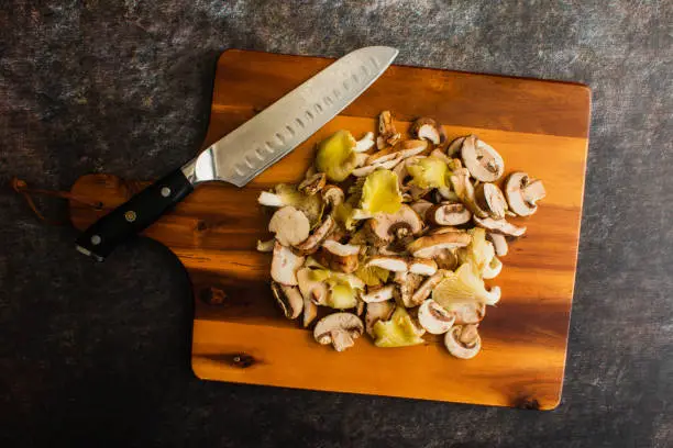 Prepped oyster, shiitake, and crimini mushrooms piled up on a chopping board