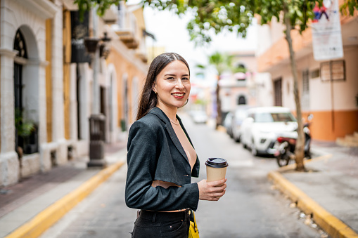 Portrait of young businesswoman with coffee outdoors