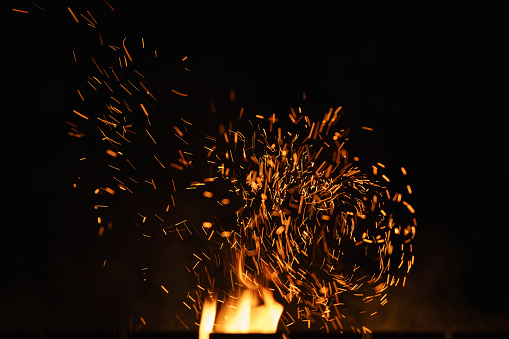 closeup hot spark from campfire over night sky, shallow focus
