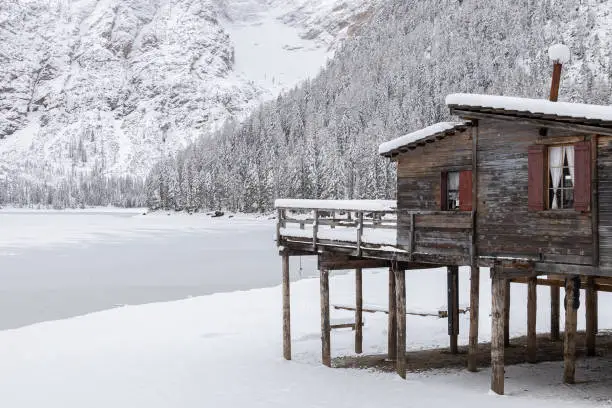 View of a wooden hut and Braies Lake completely iced in a snowy winter day; Dolomites; Alto-Adige, Italy