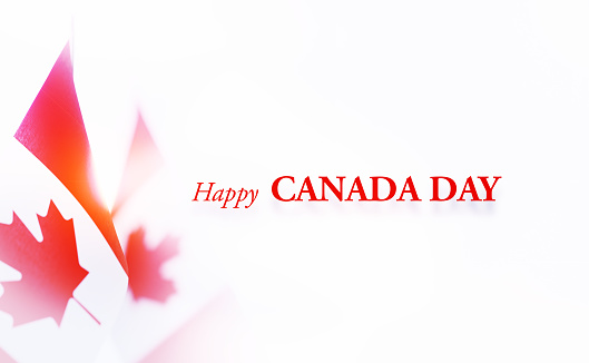 Happy Canada Day message next to Canadian flag pair on white background. Horizontal composition with copy space.