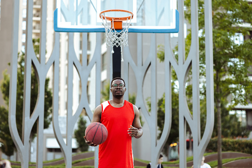 African American man holding basketball ball and standing on a sports court