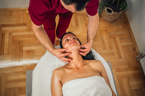 Young woman enjoying a face massage from a professional masseur