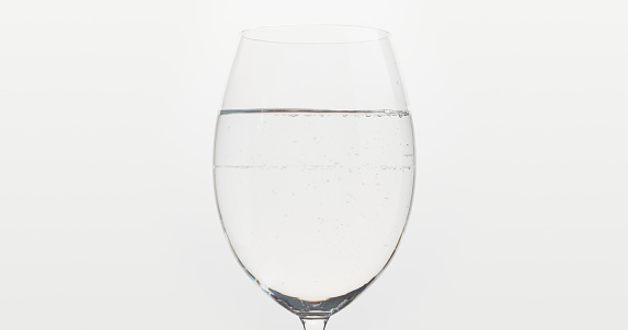 poured water into wine glass over white background, wide photo