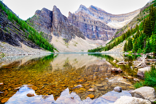 Lake agnes lies still like a sheet of glass on a summer day in the Canada rockies