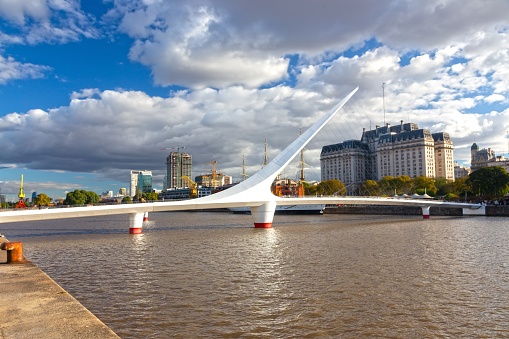 Buenos Aires, Argentina - April 15, 2023: The Women's Bridge Puente De La Mujer, pedestrian cable-stayed bridge, Puerto Madero with Urban Highrise Buildings in Background