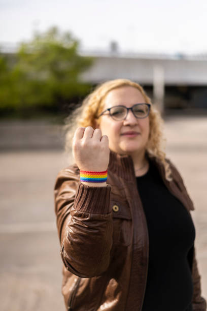 giovane donna bionda che mostra il braccialetto lgbt - gay pride wristband rainbow lgbt foto e immagini stock