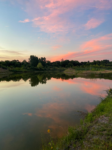 Waco sun setting over small bass pond. With a reflection that clear it is hard to tell which way is up. The reflection gives a unique symmetry to a normally asymmetric scene.