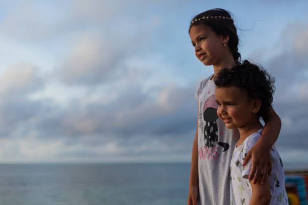 beautiful photograph of little siblings, an 8-year-old girl and a 4-year-old boy together watching the sunrise on the beautiful island of San Andres while showing the love they have
