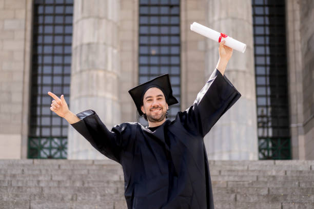 istock Confident man in graduation outfit, male obtaining degree, academic career 1497272820