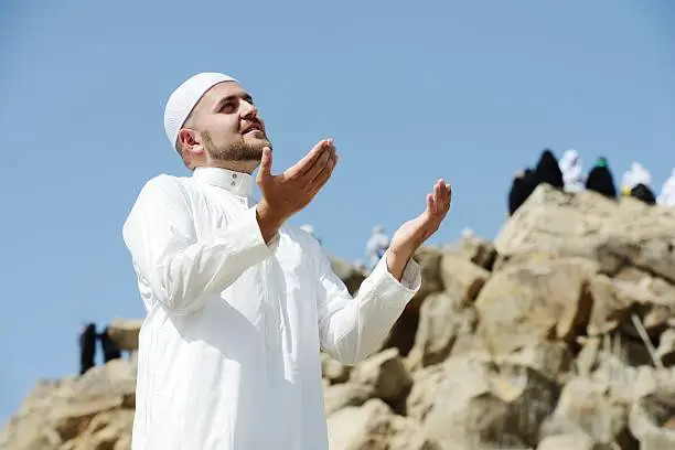 Photo of Muslim standing and praying at jabal Arafat close to Makkah