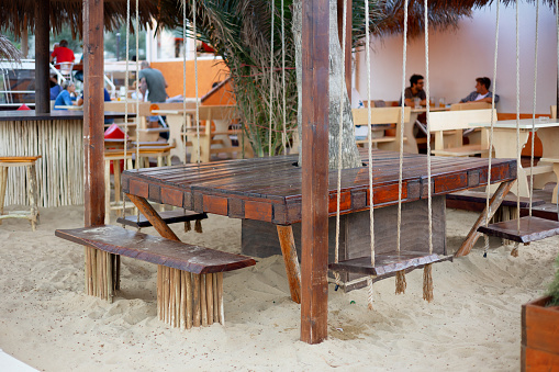 Viserbella,Italy-September 10,2022:Beautiful wooden picnic table and benches on sandy beach. Vacation concept