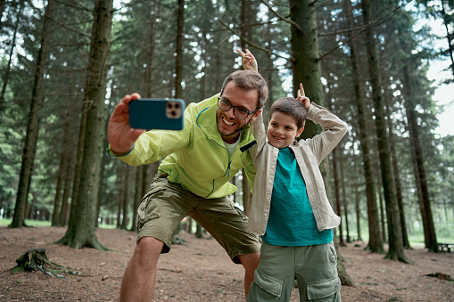 Father and son having fun while taking a selfie in the nature