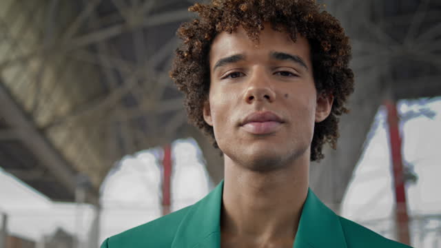 Elegant guy smiling camera at street closeup. Curly hair model posing portrait