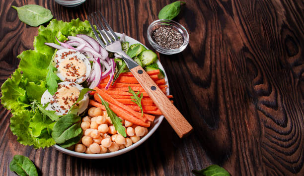 istock Boiled eggs, chickpeas with lettuce and vegetables sprinkled with flax and chia seeds. Healthy lunch menu. Keto food. Side view. Wooden background. 1497299311