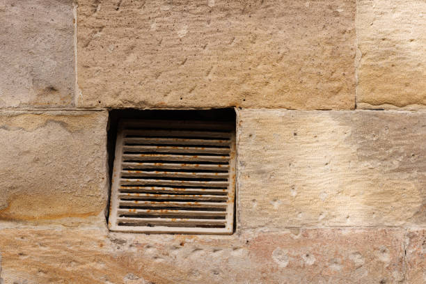 Old rusty broken metal air duct in a sandstone wall