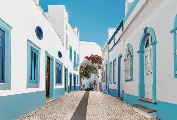 Street in fishing village. Street in fishing village with white and blue houses and typical Portuguese pavement in Olhao, Algarve region - Popular travel destinations in Portugal algarve stock pictures, royalty-free photos & images