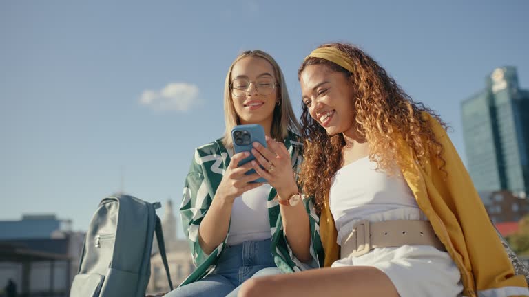 Happy woman, friends and phone on rooftop in city for social media, communication or networking. Women smile for discussion, talking or online browsing on mobile smartphone app together in urban town