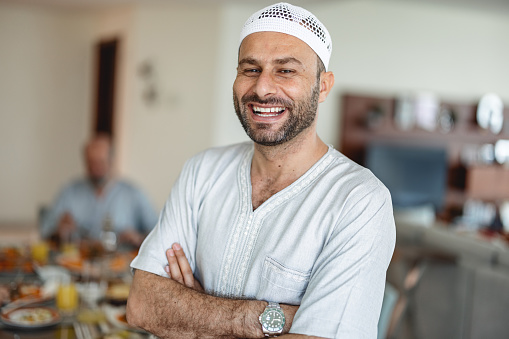 Retrato de cerca del padre del Medio Oriente sonriendo y parado frente a la mesa del comedor photo