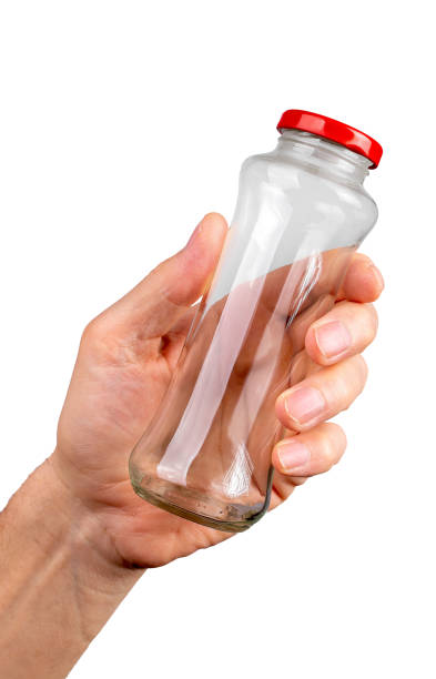 istock Hand holding empty glass bottle jar closed with red cap isolated on white background 1497318414
