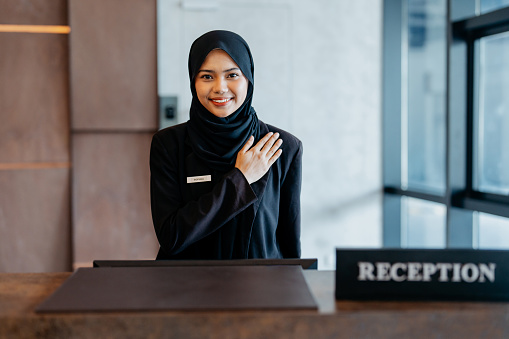 Portrait of a female Malaysian hotel receptionist smiling and looking at camera