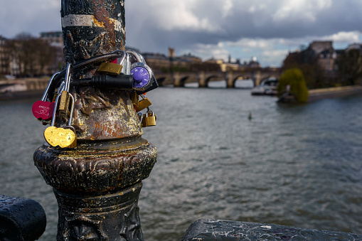 Love locks on a lamp post in Paris, France with river Seine in the background in spring