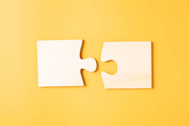 Matching two pieces jigsaw puzzle on yellow background. Creative and idea concept. stock photo