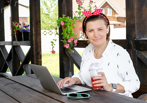 Freelance concept. Pretty woman using laptop in outdoor cafe terrace . Work and travel in hot summer
