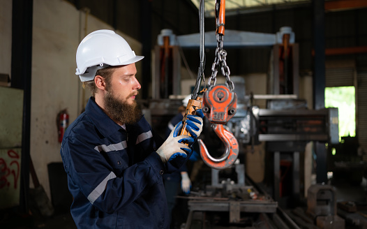 Two technicians inspecting and testing the operation of lifting cranes in heavy industrial plants.