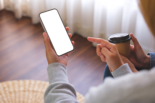 Mockup image of a couple woman holding and using a white mobile phone with blank desktop screen together