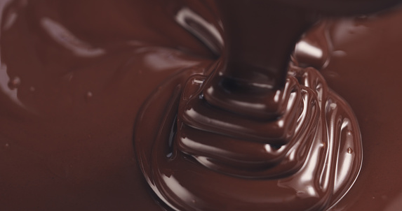 premium dark melted chocolate being poured from spoon in right part of frame from above toned, 4k photo
