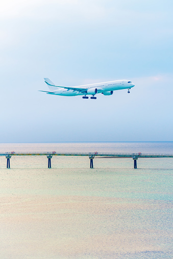 A passenger plane soaring above the glistening sea, preparing for its imminent landing.