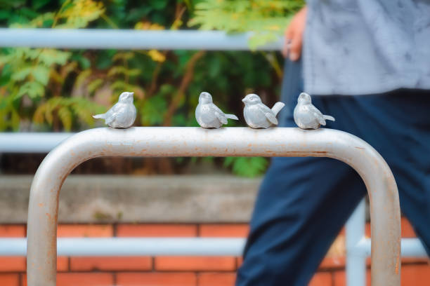 Metal railing adorned with four delightful bird sculptures. A figure walked by.