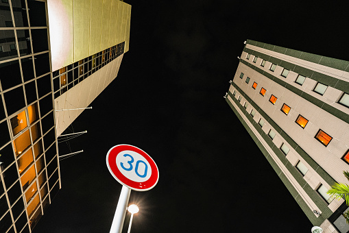 two towering buildings, a prominent speed limit sign setting a pace of 30.