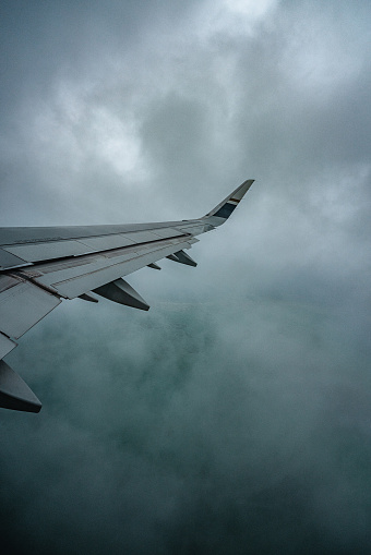 The view of the majestic airplane wing navigating through the dark cloudy.