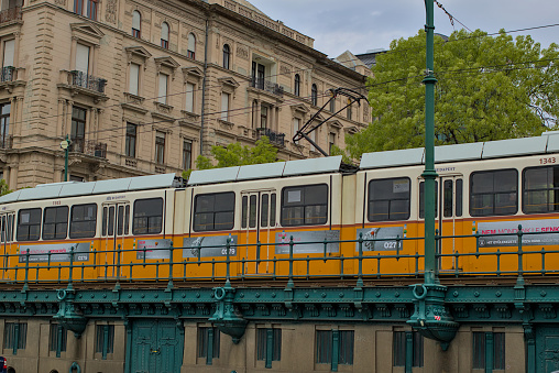 Budapest, Hungary - April 28, 2023: The famous yellow retro tram line number 2 along the Danube river. Scenic tram ride. Tourists visiting the sights of the old city.