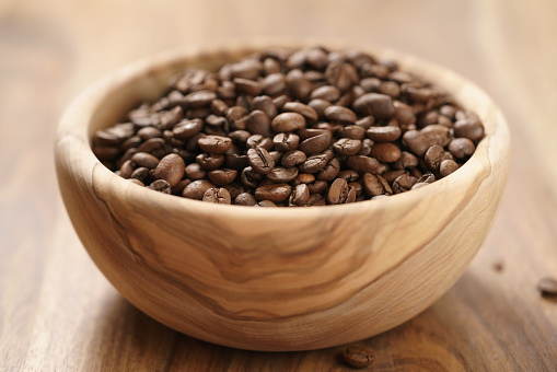 roasted coffee beans in wood bowl on table, shallow focus
