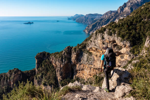 Praiano - Man with backpack enjoying scenic view from hiking trail between Positano and Praiano at the Amalfi Coast, Campania, Italy, Europe Man with panoramic view from hiking trail Path of Gods between coastal towns Positano and Praiano. Trekking in Lattari Mountains, Apennines, Amalfi Coast, Campania, Italy, Europe. Mediterranean Sea praiano photos stock pictures, royalty-free photos & images