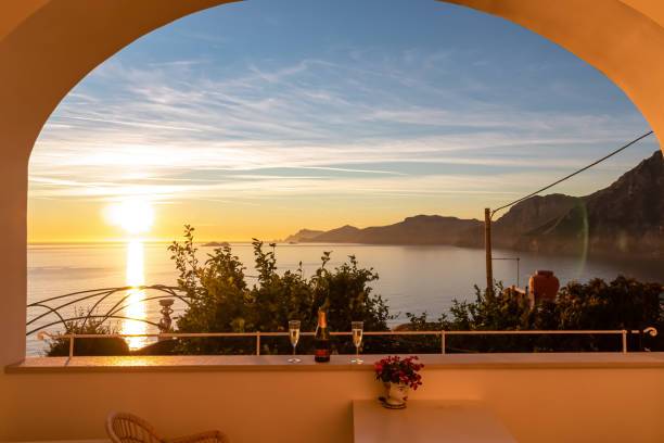 Praiano - Drinking champagne with view from a luxury apartment on the Mediterranean Sea in Praiano, Amalfi Coast, Campania, Italy, Europe. Champagne bottle with scenic sea view during sunset from luxury apartment on Mediterranean Sea. Terrace balcony with arch overlooking the coastline in Praiano, Amalfi Coast, Campania, Italy, Europe praiano photos stock pictures, royalty-free photos & images