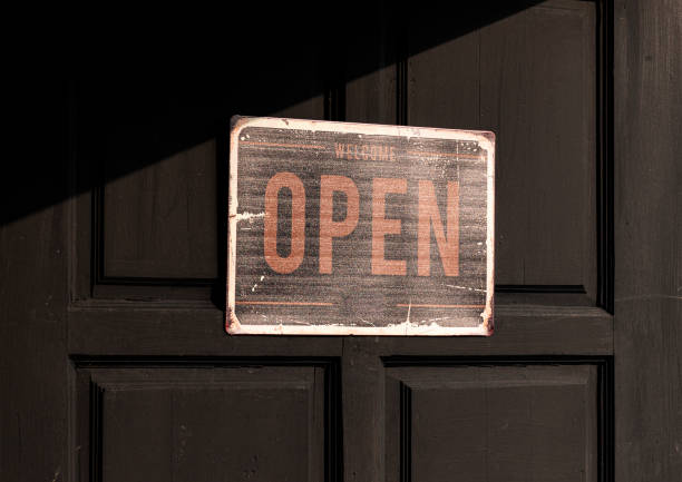 istock Sign with message Welcome OPEN on black wooden door 1497344311