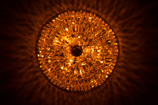 Glass chandelier with a yellow-orange glow on the ceiling