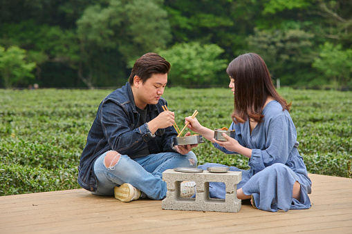 Young Asia couple eating lunch box in the tea garden.