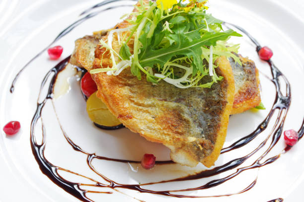 Crispy seared sea bass with pomegranate seeds and balsamic vinegar garnish