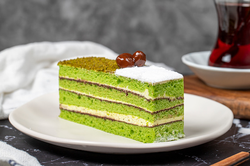Mini slice colorful green pistachio cake. Delicious cream cake on dark background. Close up