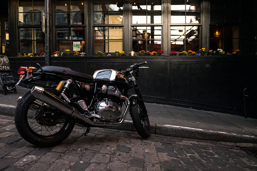 Seattle, USA - May 29, 2023: Late in the day a vintage Royal Enfield motorcycle parked in the famous Post Alley in Pike Place Market.