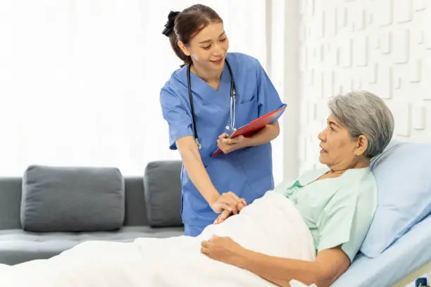 Photo of Medical personnel visit female patient lying in bed to inquire about symptoms