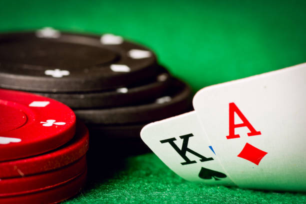 Gambling chips, ace of diamonds and king of spades on green poker cloth.