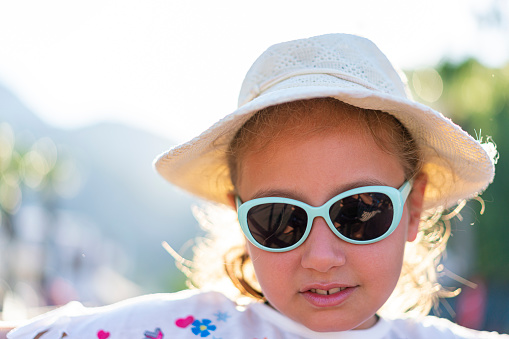 Portrait of a girl with cap and sunglasses at the beach