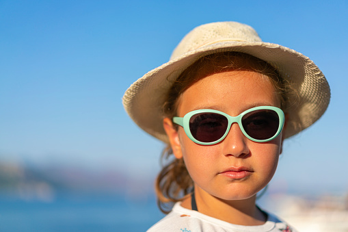 Portrait of a girl with cap and sunglasses at the beach